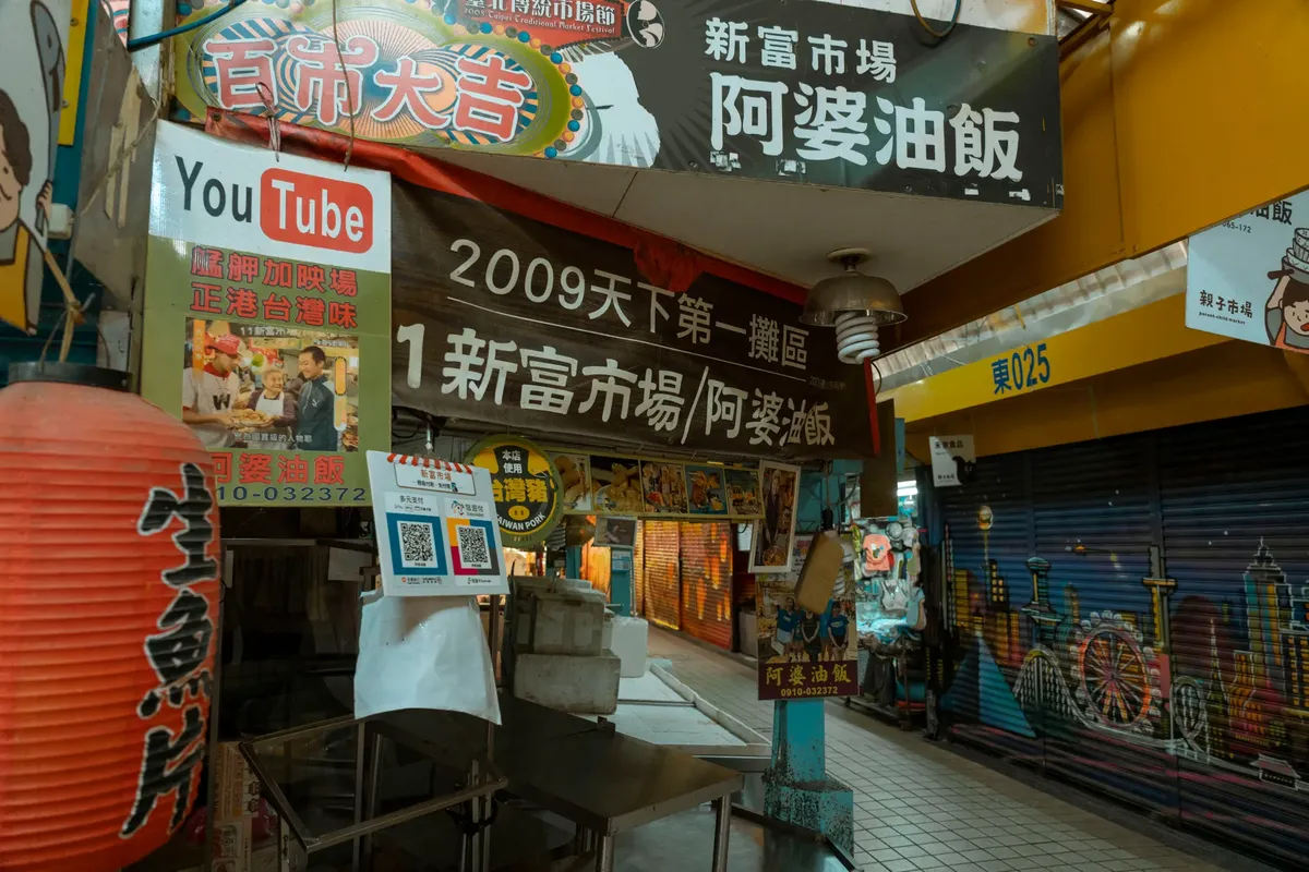Explore a bustling urban street market adorned with colorful banners and signs, showcasing local culture and cuisine.