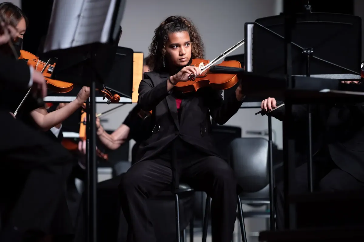 Black woman violinist performing at a concert, focused on her music.