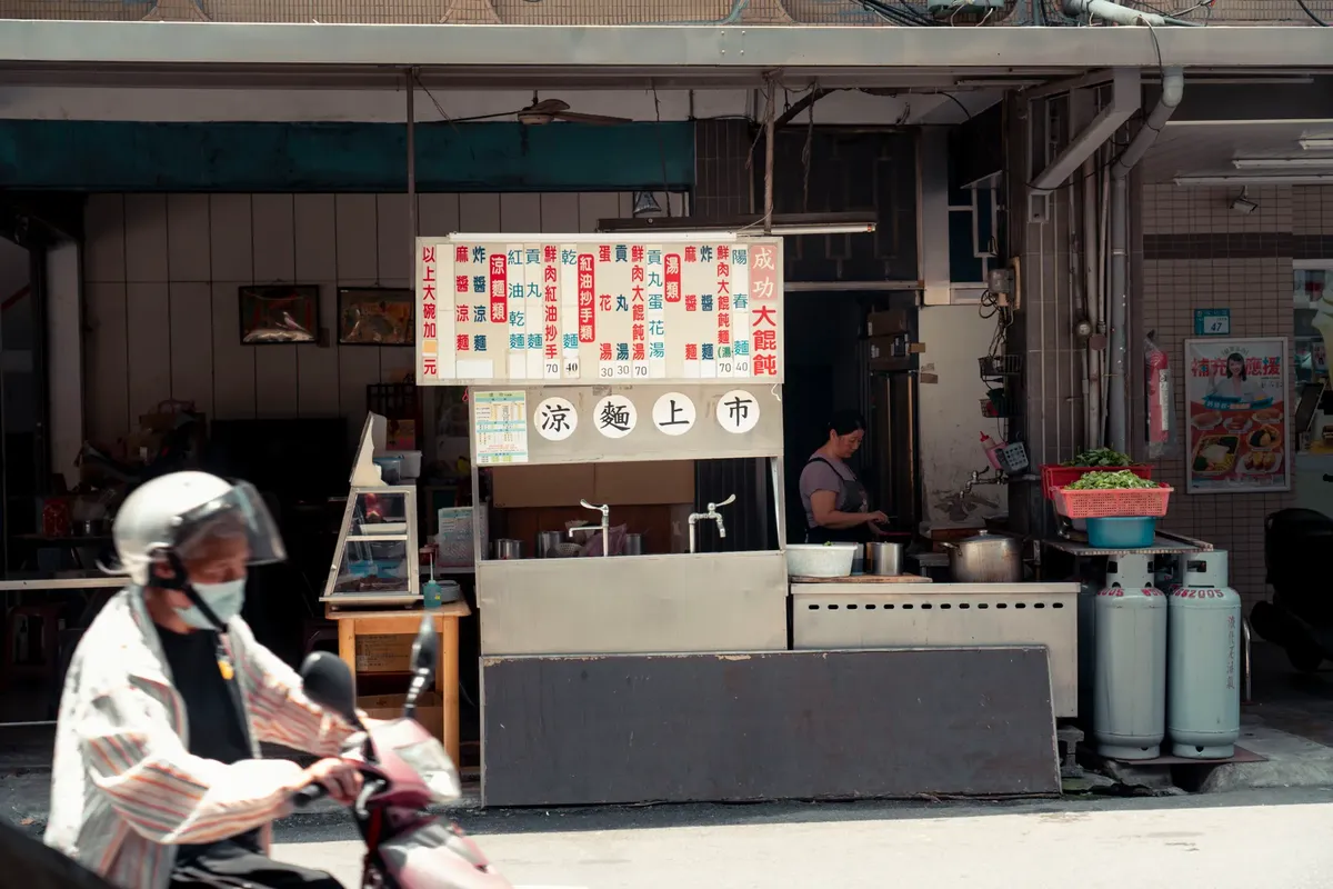 Traditional noodle stall with a scooter passing by in New Taipei City, Taiwan.