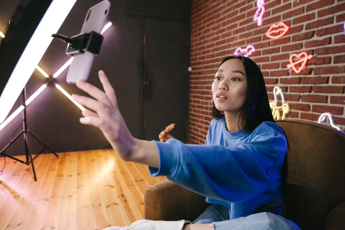 アジアの女性がスタイリッシュなネオンライトの部屋でライブストリームコンテンツを制作している